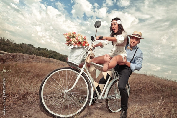 Fototapeta Groom and bride on a bicycle with just married sign and cans attached
