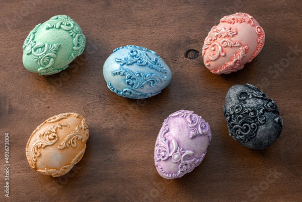 Fototapeta Six embossed carved vintage Easter eggs on a dark wooden background. Easter background with unusual Art Nouveau style Easter eggs on the side and space for text on the right. Top view.