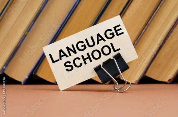 Fototapeta On the table against the background of books is a business card with the inscription - language school