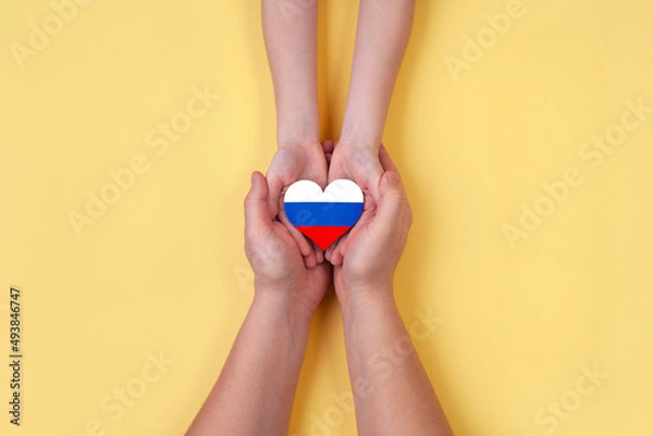 Fototapeta Men's hands and a child's hands hold together a heart with the flag of Russia. A world without war!