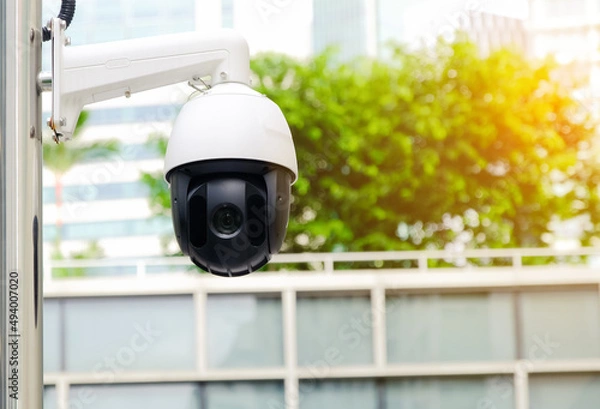 Fototapeta Modern public CCTV camera on electric pole with blur building background. Recording cameras for monitoring all day and night. Concept of surveillance and monitoring with copy space.