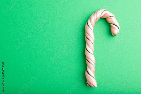 Fototapeta Single cane candy on green background. copy space, top view