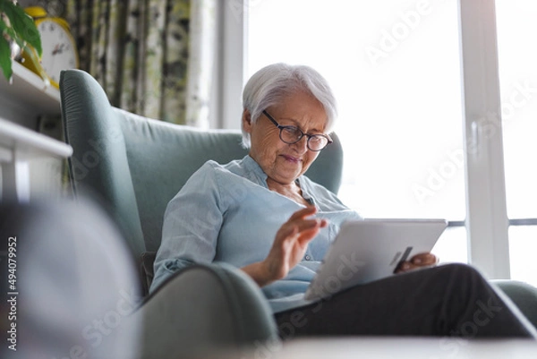 Obraz Senior woman using a digital tablet at home
