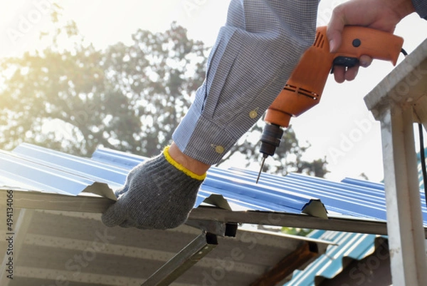 Fototapeta A male mechanic installs the roof of the house with all the equipment used for installation with skill