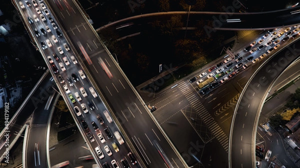 Fototapeta Aerial top down of multilevel elevated road huge traffic junction in modern metropolis city. Night long exposure motion blur of vehicles. Modern development of infrastructure and motorways in China.