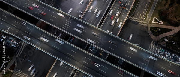 Fototapeta Aerial top down of multilevel elevated road huge traffic junction in modern metropolis city. Night long exposure motion blur of vehicles. Modern development of infrastructure and motorways in China.