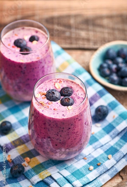 Fototapeta Blueberry smoothie in glass. Homemade blueberry smoothie on rustic wooden table. Blueberry smoothie with yogurt and oats.