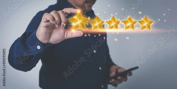Fototapeta Businessman holding virtual five yellow stars on hands. Evaluation the customer satisfaction and service. Products and service evaluation concept.