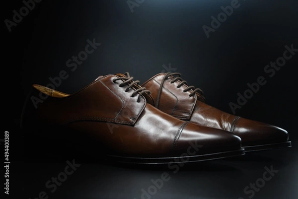 Fototapeta Photo of dark brown shoes on black background
