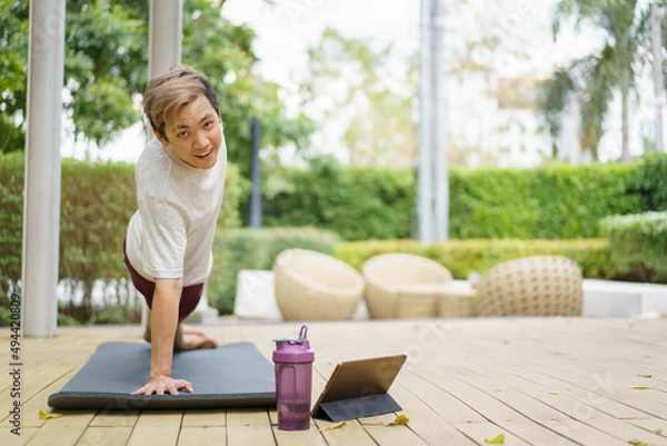 Fototapeta Active sportsman doing a side plank exercise and making a video call with a friend and online sport training coach. 