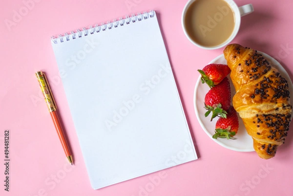 Fototapeta Pink note with pencil and sharpener, coffee cup, croissant with strawberries on pink background