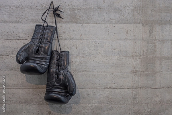Obraz black boxing gloves hanging on a change room,  concrete wall