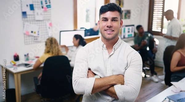Fototapeta Were in it to win it. Portrait of a confident young businessman working in a modern office with his team in the background.
