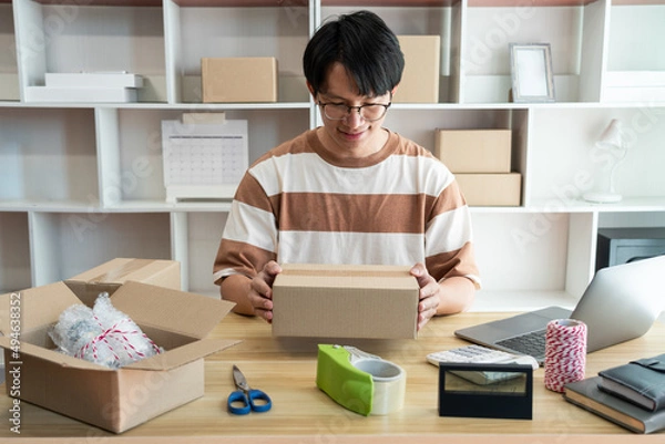 Fototapeta Online shopping concept the online shop agent packing his product into the box and sealing it deliberately