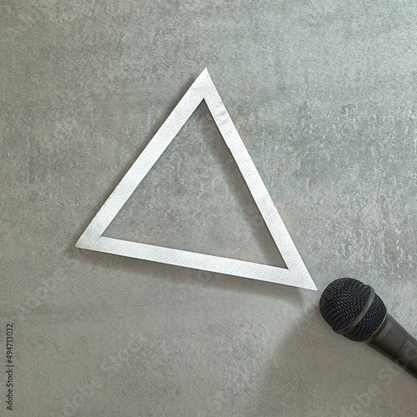 Fototapeta Simply. Microphone and silver triangle frame on gray concrete background. Text space. Top view. Minimal style.