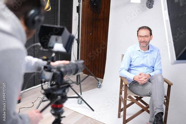 Fototapeta young man video camera operator making interview in professionnal broadcast tv movie studio film production