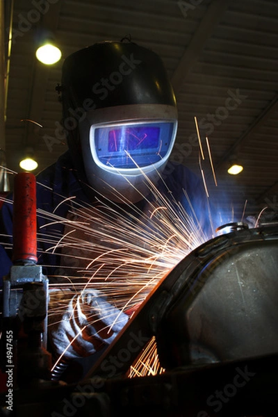 Fototapeta Welder welding a metal part in an industrial environment