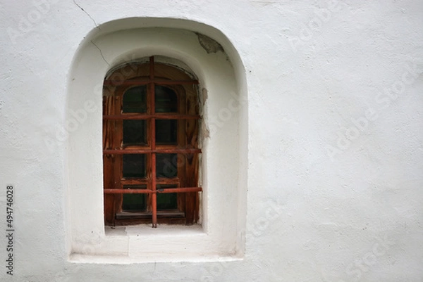 Fototapeta Window in a niche on the plastered wall of the Church of John the Baptist in the city of Veliky Novgorod. From the Window of the World series.