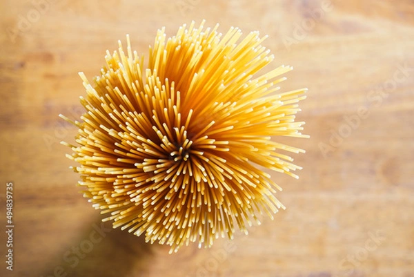 Fototapeta Yellow long spaghetti on a rustic background. Yellow italian pasta. Long spaghetti. Raw spaghetti bolognese. Raw spaghetti. Food background concept. Italian food and menu concept.