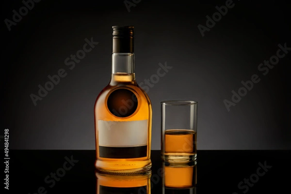 Fototapeta Bottle and glass with whiskey, cognac, brandy on a black background.