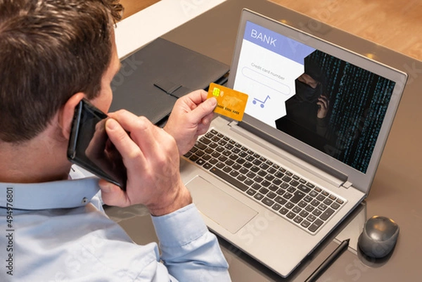 Fototapeta Man making purchases with his credit card over the phone while being scammed by a cyber thief. Vishing scam