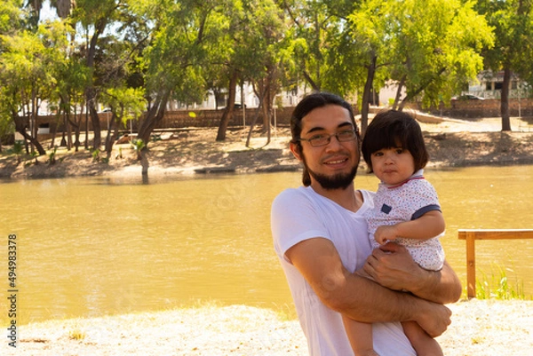 Obraz portrait of a Hispanic father and baby in a park smiling and having fun