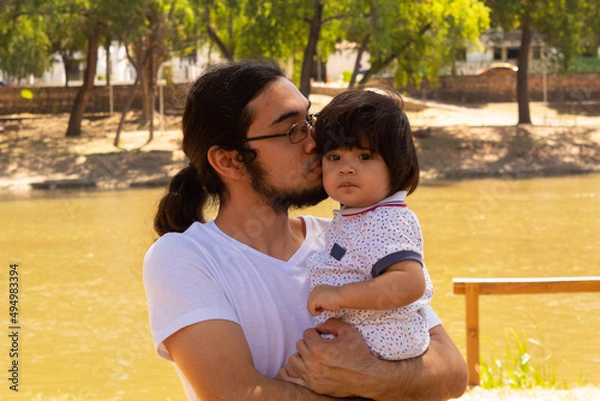 Obraz portrait of a Hispanic father and baby in a park smiling and having fun
