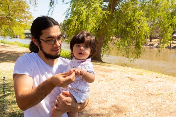 Obraz portrait of a Hispanic father and baby in a park smiling and having fun