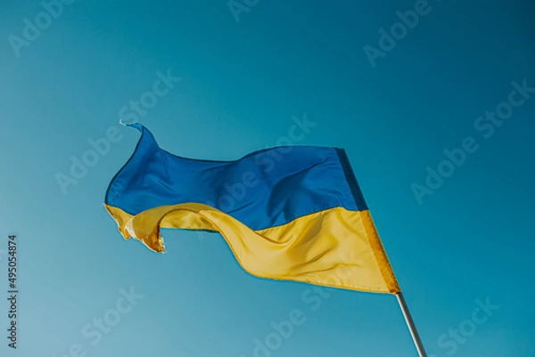 Obraz The flag of Ukraine is a large national symbol flying in the blue sky. Large yellow and blue state flag of Ukraine.