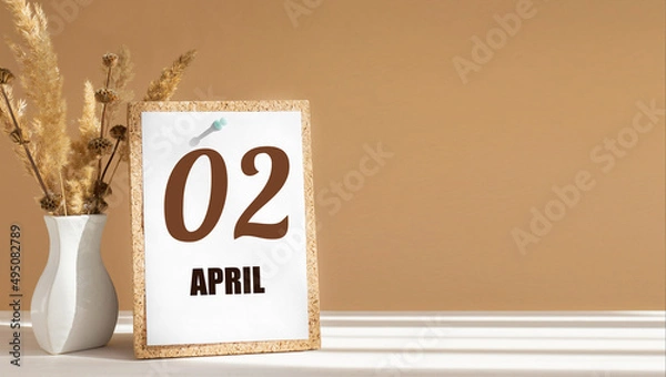 Fototapeta April 2. 2th day of month, calendar date.White vase with dead wood next to cork board with numbers. White-beige background with striped shadow. Concept of day of year, time planner, spring month