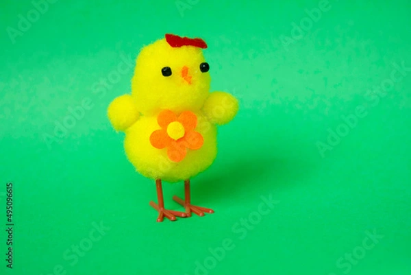 Fototapeta Toy chicken on a green background. Cute fluffy yellow Easter chicken. Cope space. Easter. Bird. Children is toy
