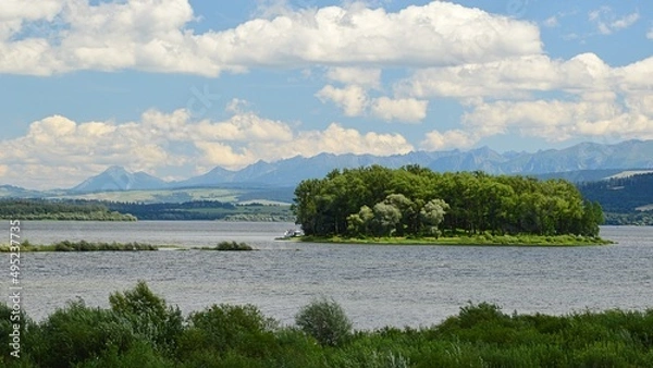 Fototapeta Landscape with Slanica Island Of Art in center of Orava river dam in northern Slovakia covered with mostly broadleaf trees, during beautiful partially cloudy summer day.