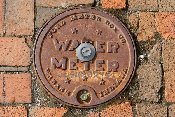 Fototapeta Rusted water meter access hatch on a brick street