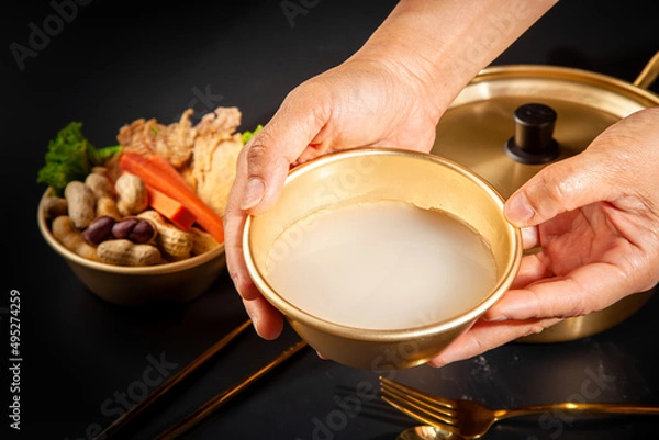 Fototapeta Makgeolli rice wine is a Korean fermented alcoholic beverage traditional drinks. 
Korean alcoholic drink (Makgeolli) in a traditional Korean gold liquor bowl with snack on Black background. 