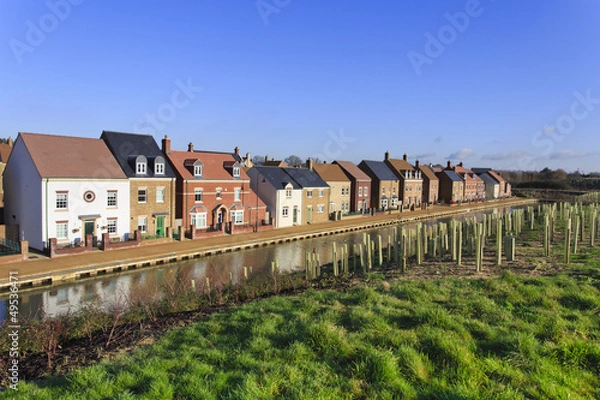 Fototapeta Brand new luxury houses by a canal with trees planted