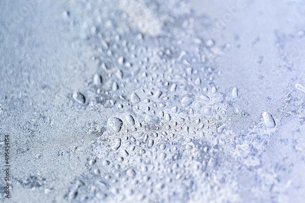 Fototapeta Beautiful texture of ice crystals and frozen water droplets on the glass. Winter silver-blue light background