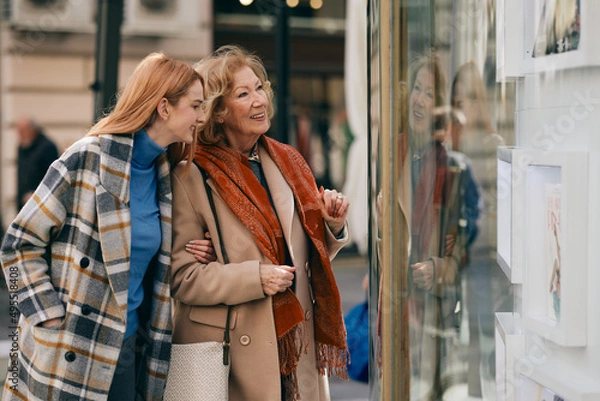 Obraz Happy grandmother and granddaughter looking at show window at the gallery.
