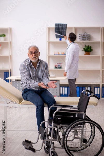 Fototapeta Old injured man visiting young male doctor radiologist