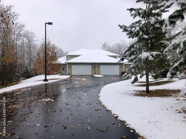 Obraz Asphalt driveway leading to a twin home or duplex has many wet leaves on it, following a recent snow fall, on an overcast autumn day in Minnesota.