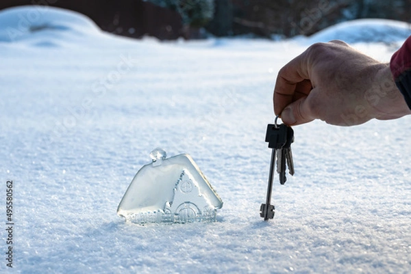 Fototapeta beautiful miniature glass, crystal house and man's hand with keys on background of white snow. Concept of dream house. Copy space
