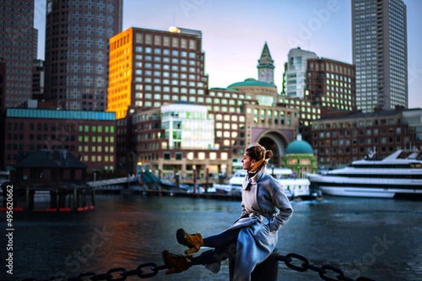Obraz girl in coat against the backdrop of the cityscape yachts and riverboats moored in Boston harbor