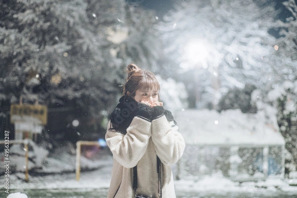 Fototapeta 雪が降る中冷える手を温める女性