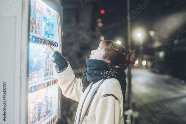 Fototapeta 深夜の自動販売機で飲み物を選ぶ女性