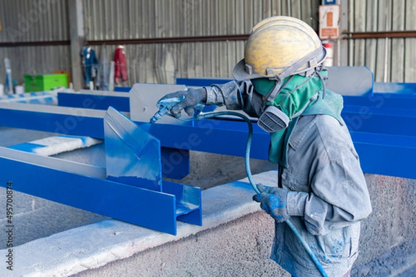 Fototapeta Painter is working to paint color topcoats on steel structures with a spray gun at the industrial factory, focusing on hand holding a spray gun.