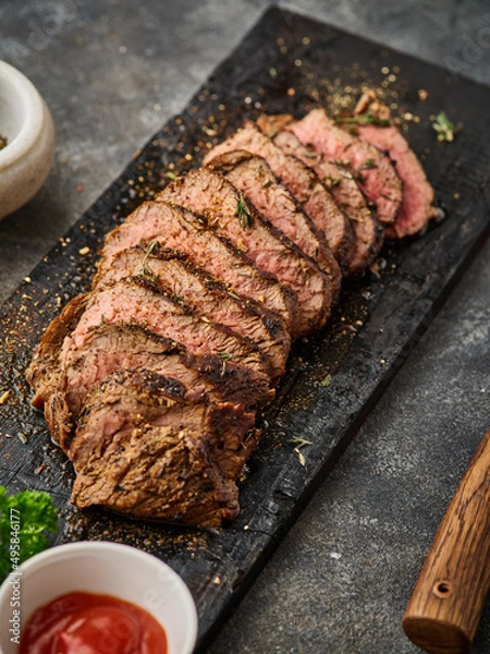 Obraz Grilled sliced beef steak on cutting board over grey table. Beef tenderloin steak. Filet Mignon recipe.