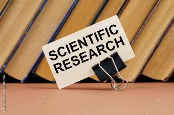 Fototapeta On the table against the background of books is a business card with the inscription - Scientific Research