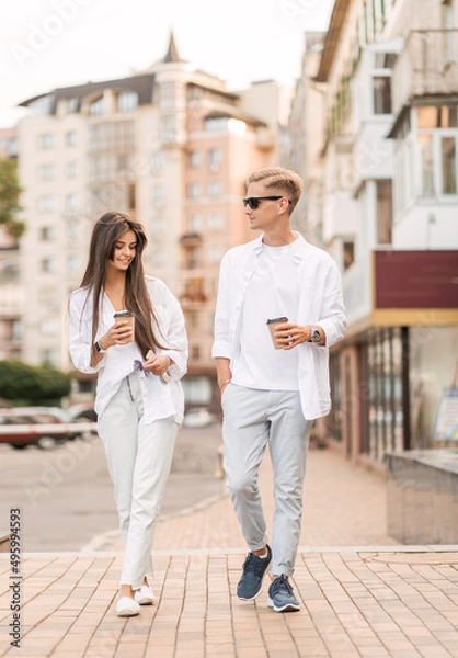 Obraz guy with a girl in white clothes walks around the city and drinks coffee