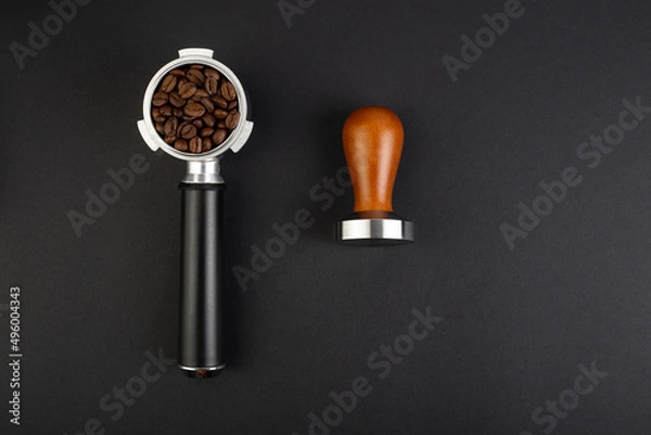 Fototapeta Barista Kit. Coffee Tamper with Brown Wooden Handle and coffee horn with beans. Top view on black background. Barman tool for pressing down ground coffee, a tamper for a coffee machine