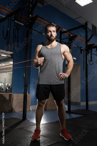 Fototapeta man exercising in the gym with rubber bands