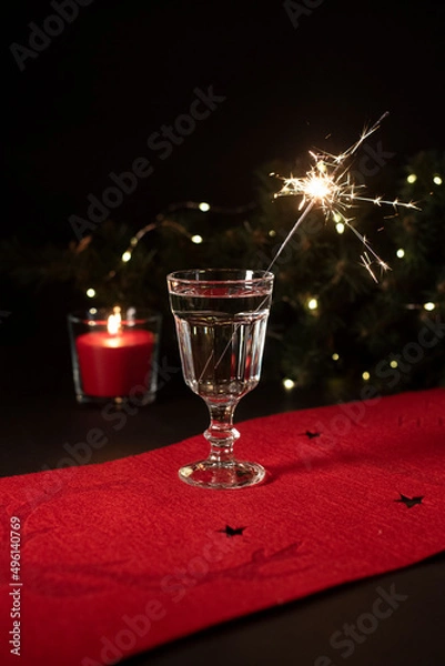 Fototapeta Festive beverage with the sparkler in it on a black background. Christmas decorations